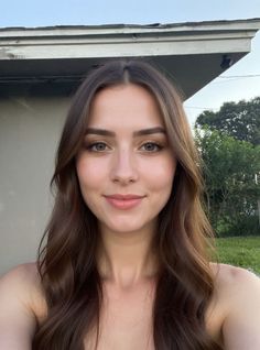 Woman with long brown hair and green eyes smiling outdoors