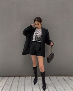 Woman in a black blazer and shorts with knee socks and pointed heels