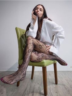 Woman in a white shirt and lace tights sitting on a green chair