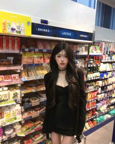 Woman with long black hair in a black dress inside a convenience store