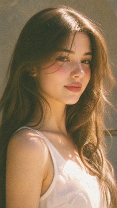 Woman with long brown hair in a white tank top with soft lighting
