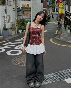 Woman in a plaid top and wide leg pants standing on a street