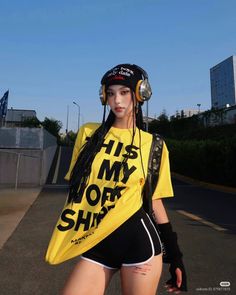 Woman with braided hair wearing a yellow t-shirt and headphones outdoors