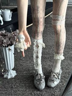 Person in lace tights and ruffled socks holding a small toy lamb