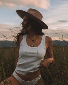 Woman in a tank top and underwear wearing a cowboy hat in tall grass