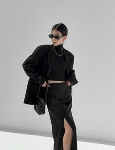 Woman in a black blazer and skirt with a high slit in a studio