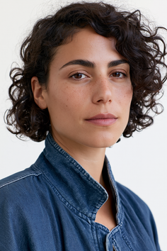 Woman with curly hair and freckles wearing a denim jacket