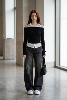 Woman with long red hair wearing an off-shoulder top and wide-leg jeans indoors