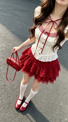 Person in a red skirt and white top holding a red handbag outdoors