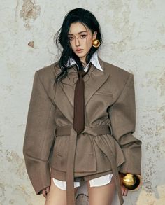 Woman in an oversized blazer with a brown tie and gold accessories
