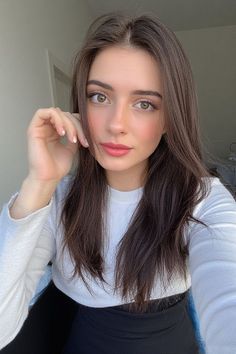 Woman with long brown hair and green eyes wearing a white shirt indoors