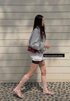 Woman with long hair in a grey jacket and lace socks walking outdoors