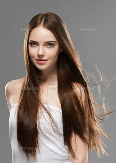 Woman with long brown hair and blue eyes wearing a white top in a studio shot