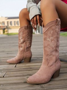 Person wearing suede cowboy boots on a wooden deck outdoors