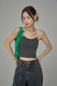 Woman in a gray crop top and denim jeans with a green fuzzy bag