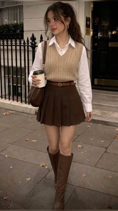 Woman in a sweater vest and pleated skirt walking on a street