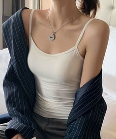 Woman in a white camisole and pinstripe jacket indoors
