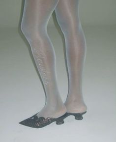 Legs in white tights with sparkling detail and black low-heeled shoes