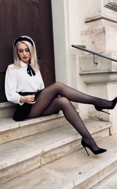 Woman with blonde hair and black tights sitting on stone steps