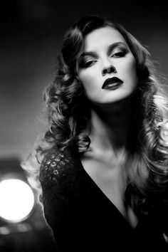 Woman with long curly hair and dark lipstick in a dramatic black and white portrait