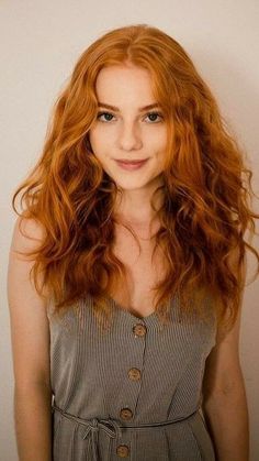 Woman with long wavy red hair wearing a striped dress with buttons
