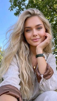 Blonde woman with long hair smiling outdoors under a blue sky
