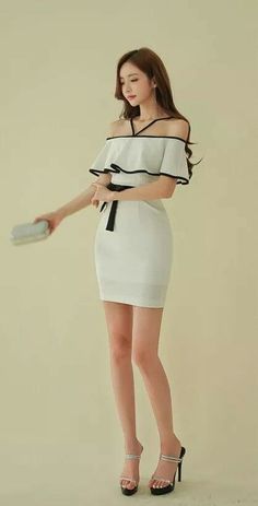 Woman in a white off-shoulder dress holding a clutch bag