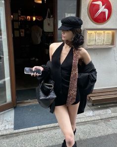 Woman in a black romper and newsboy cap with a leopard print scarf outdoors