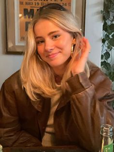 Blonde woman in a brown leather jacket smiling indoors
