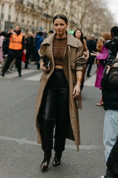 Woman in a trench coat, crop top, and leather pants on a city street
