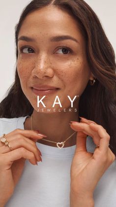 Woman with long hair and freckles wearing a heart necklace and earrings