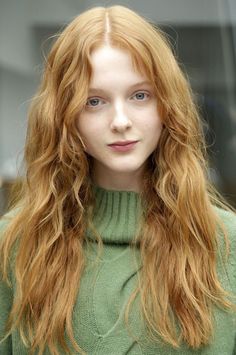 Woman with long red hair and blue eyes wearing a green sweater