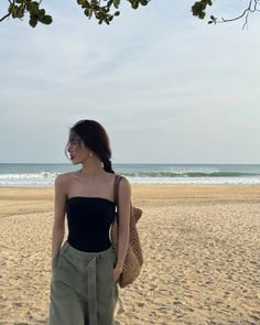 Woman in a black tube top and khaki pants on a sandy beach