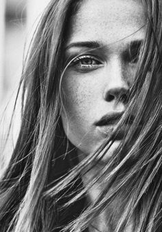 Close up black and white portrait of a woman with long hair and freckles