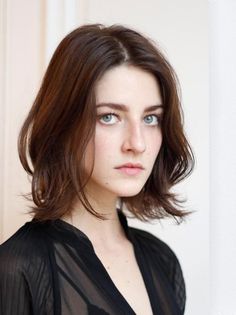 Woman with short brown hair and blue eyes wearing a sheer black top