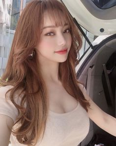 Woman with long light brown hair and a tight top, posing outdoors