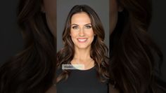 Woman with long wavy hair and green eyes smiling in a studio portrait