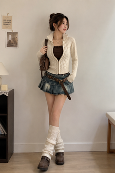 Woman in a denim skirt, cable knit cardigan, and leg warmers indoors