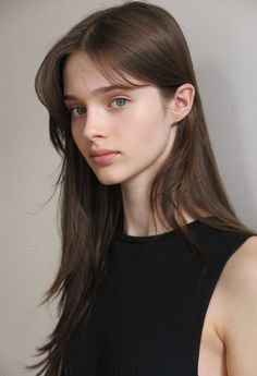 Young woman with long brown hair and green eyes wearing a black top