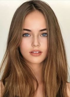 Close-up portrait of a young woman with long brown hair and blue eyes