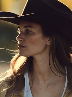 Woman in a cowboy hat with long hair backlit by golden hour sun