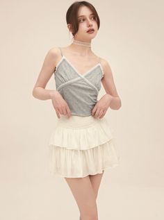 Woman in a gray camisole and white tiered skirt with a choker in a studio
