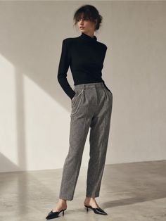 Woman in a black turtleneck and houndstooth pants with an updo hairstyle