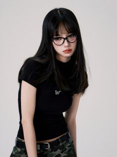 Woman with long black hair and glasses wearing a black t-shirt and camouflage skirt