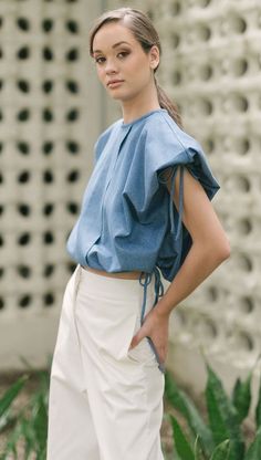 Woman in a blue top and white pants posing outdoors