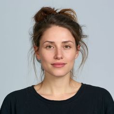 Woman with brown hair in a messy bun wearing a black t-shirt in a studio shot