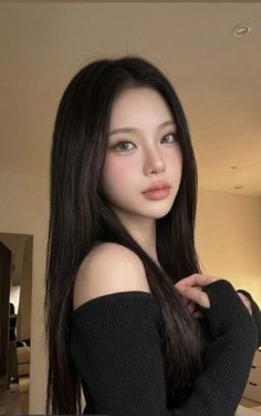 Woman with long black hair wearing an off-shoulder top indoors