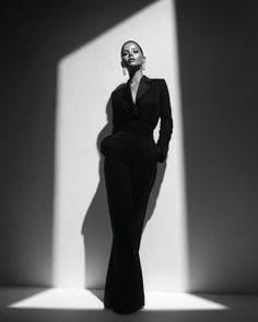 Woman in a black suit standing in dramatic lighting