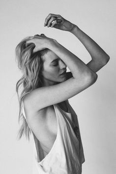 Woman in a tank top with hands in her hair, shot in black and white