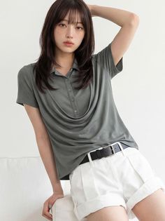 Woman with long hair and freckles wearing a polo shirt and white shorts